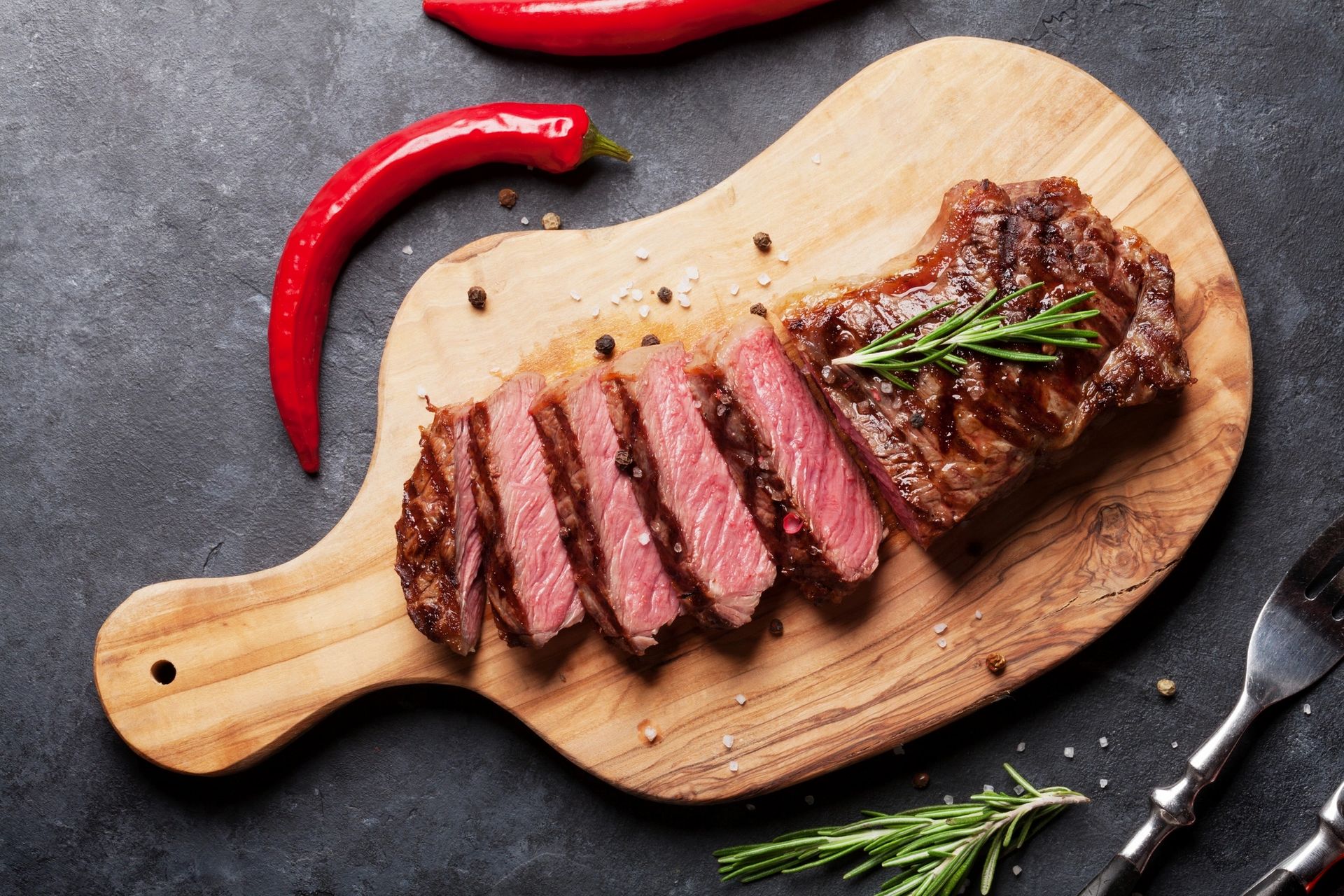A hand-cut New York strip sliced on a board
