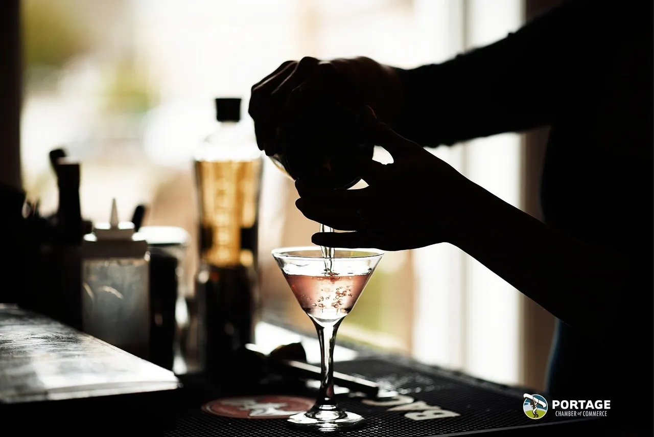 A cocktail being strained into a chilled glass