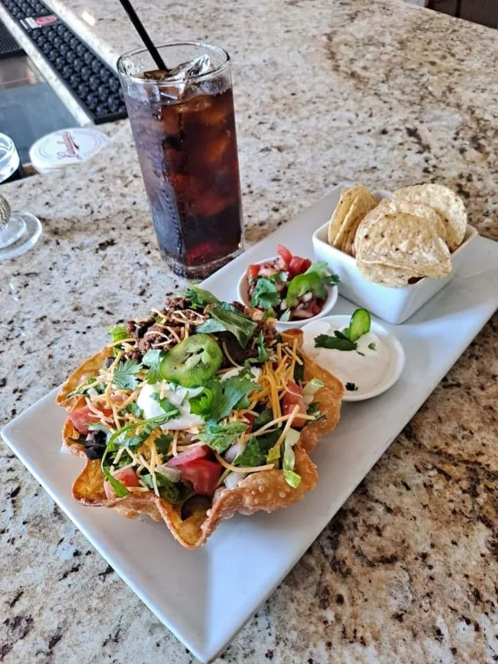 Taco salad in a crisp tortilla bowl with chips and salsa