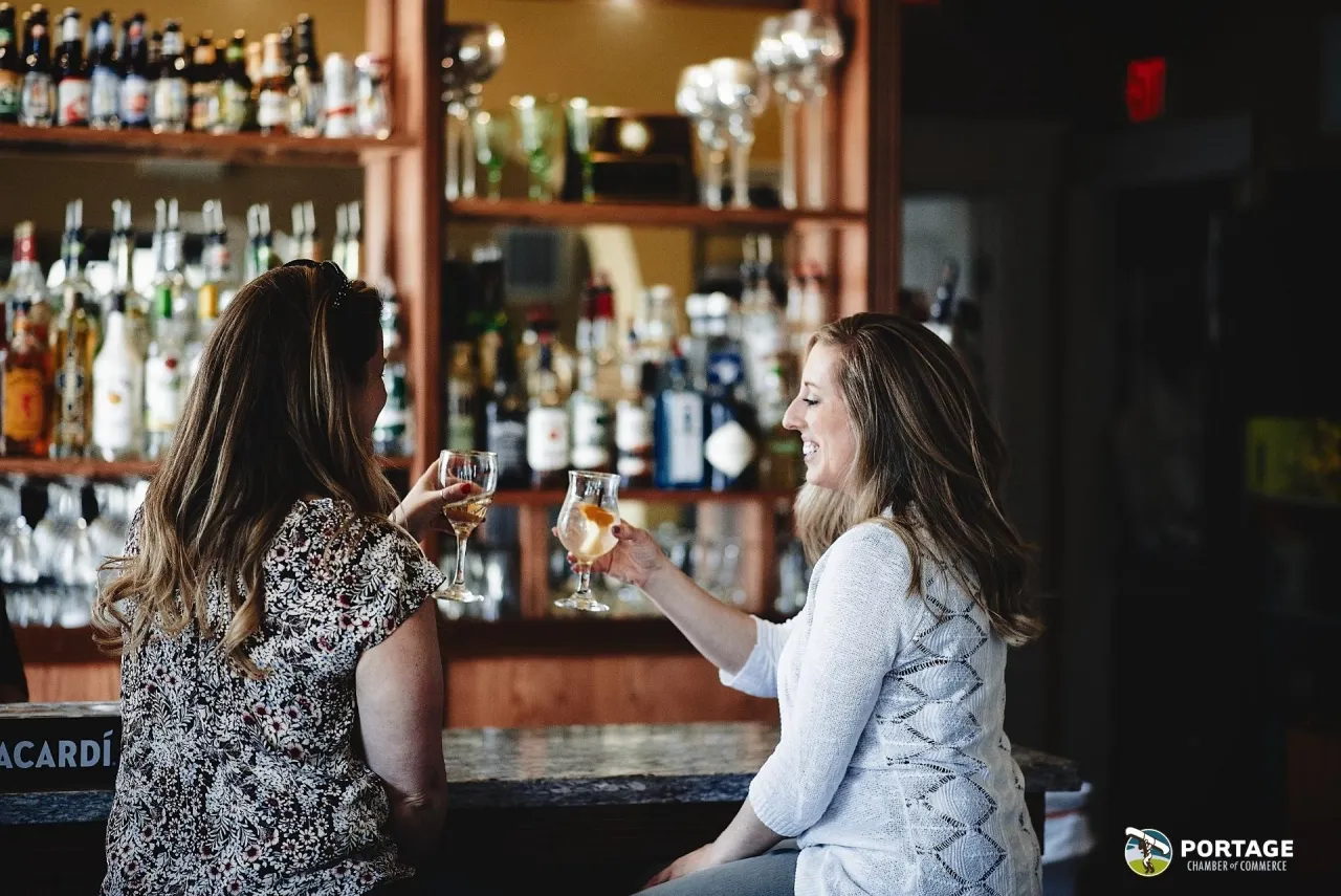 Two guests toasting with wine at the bar